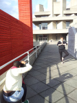 Woman demonstrating Tree in front of concrete building